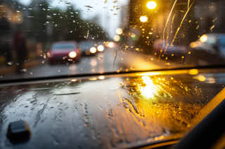 dangerous scene in traffic because the wipers don't work properly, bekeh shows pedestrians, mirrors, reflections, lanterns and cars with blinding lights, generative AI